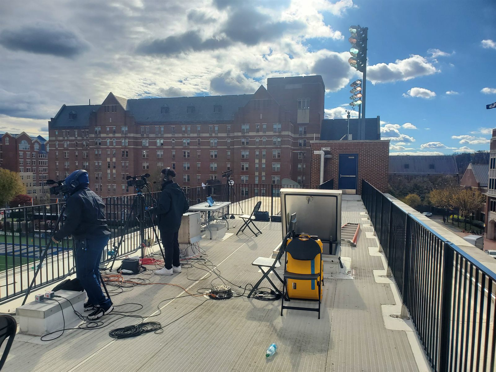 The open-air operating deck above the field on game day, with camera and clipping gear set up overlooking the stadium.