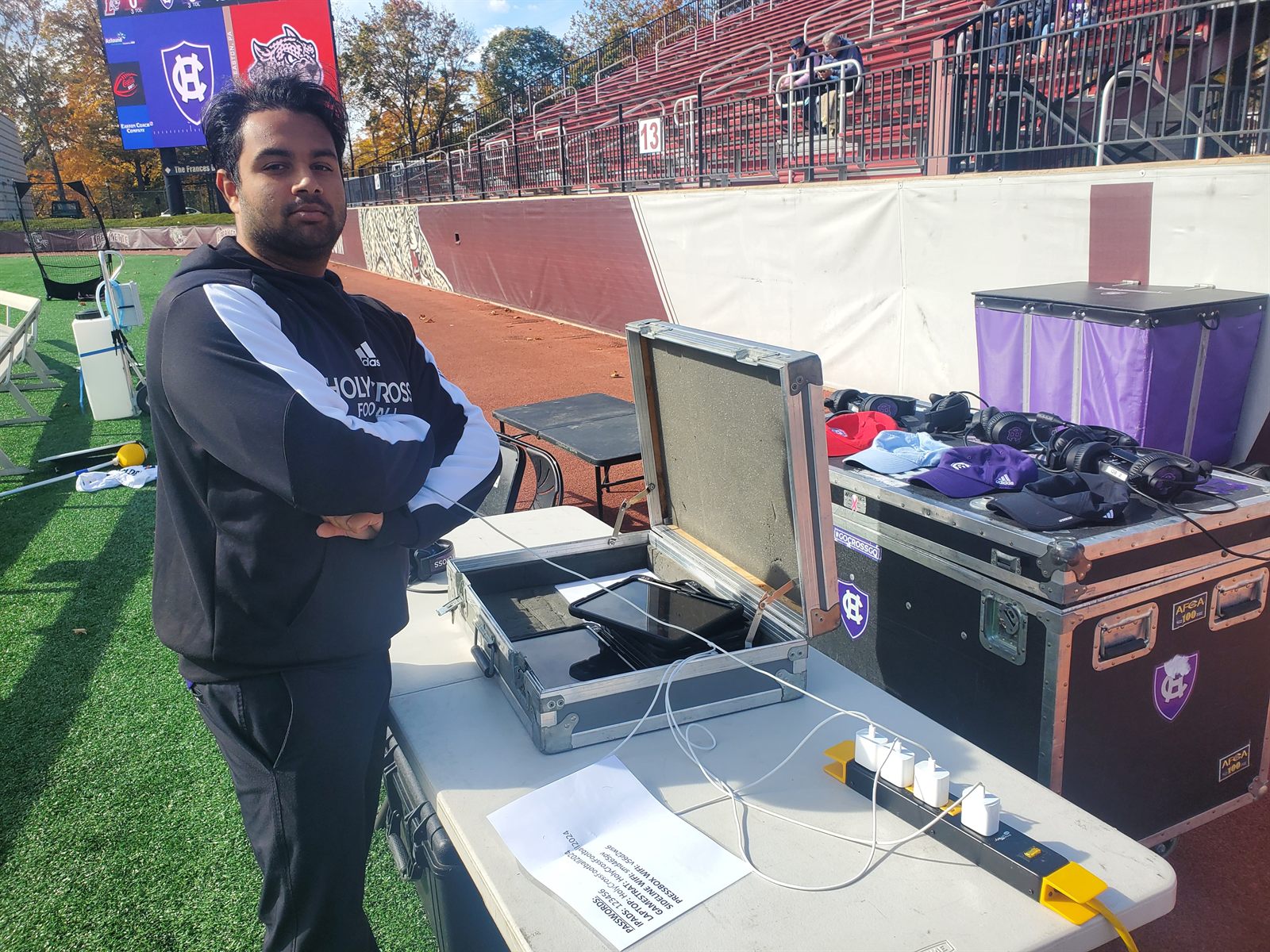 Dylan on the field beside the open Gamestrat equipment cases before a game.